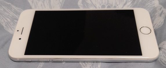 a white IPhone lying on a bed